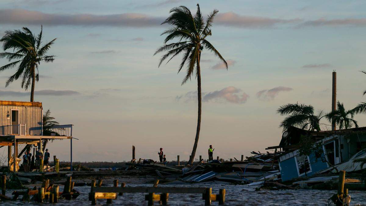 Personas cerca de las propiedades dañadas en una sección destruida de Pine Island Road, el jueves 29 de septiembre 2022, en Matlacha, Florida. El huracán Ian tocó tierra en la costa del suroeste de la Florida como una tormenta de categoría 4 dejando zonas afectadas con calles inundadas, árboles caídos y escombros esparcidos.