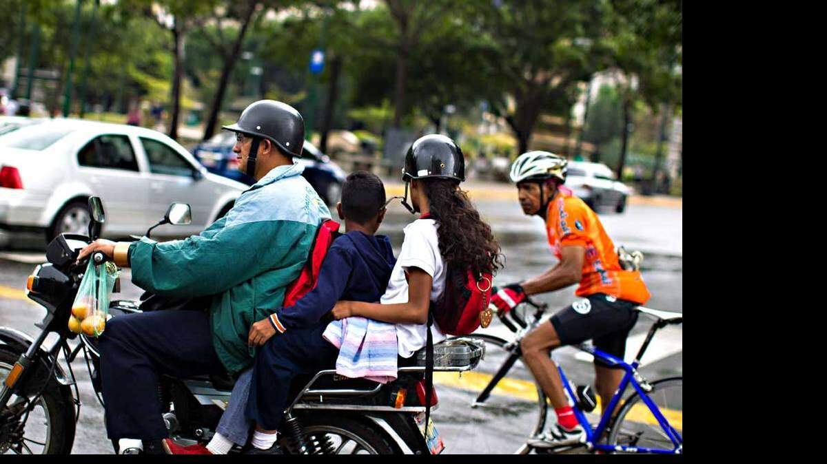 Fotografía de  agosto de 2013 de un motorizado transportando dos niños por una calle de Caracas (Venezuela).