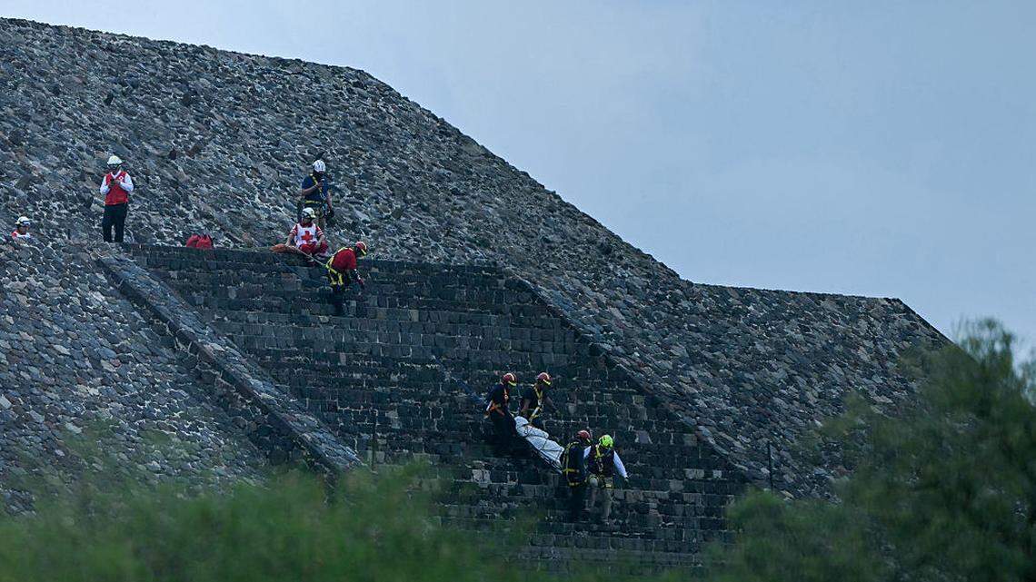 Expertos forenses y miembros de la Cruz Roja trasladan un cuerpo en la Pirámide de la Luna, en la zona arqueológica de Teotihuacán, México, tras el tiroteo ocurrido el 20 de abril de 2026. 