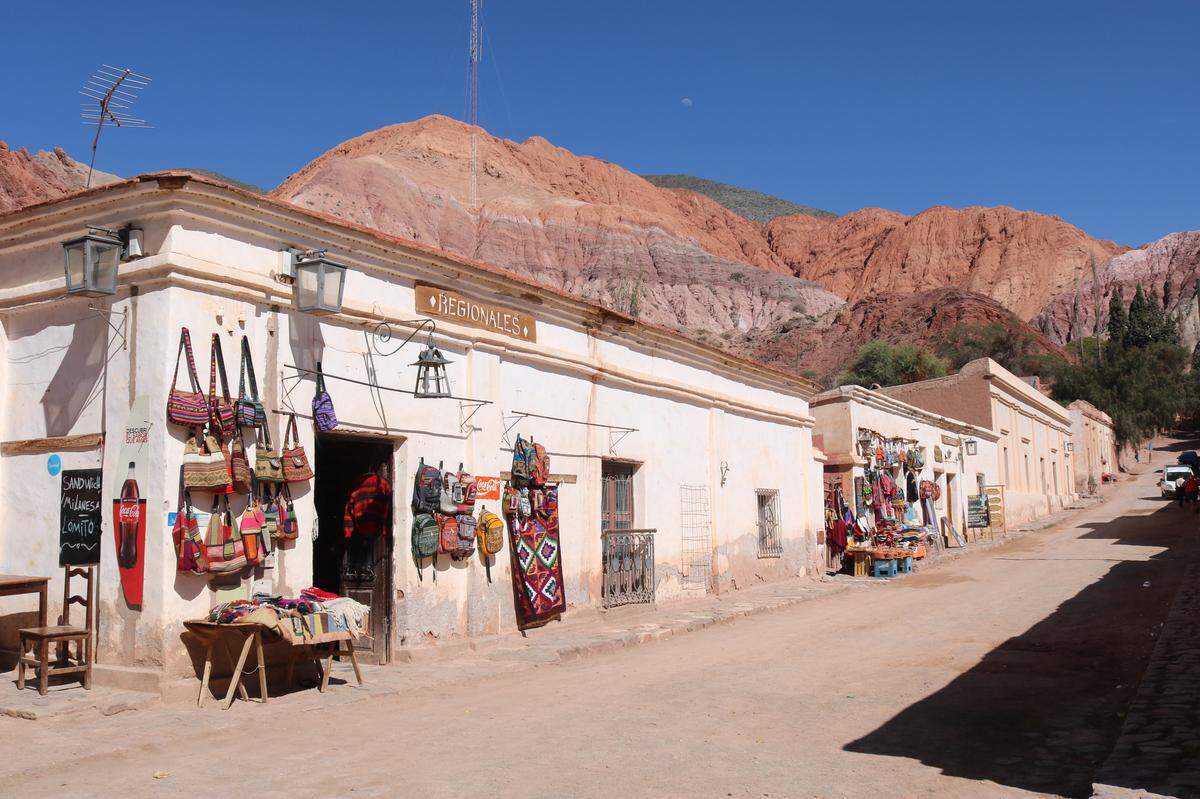 La montaña de los Siete Colores se impone detrás de las tiendas del pueblito de Cabildo, Purmamarca.