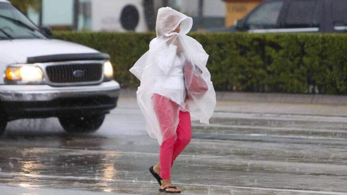 Una mujer se protege de la lluvia mientras camina en Collins Avenue el martes, 6 de junio de 2017, en Sunny Isles Beach.
