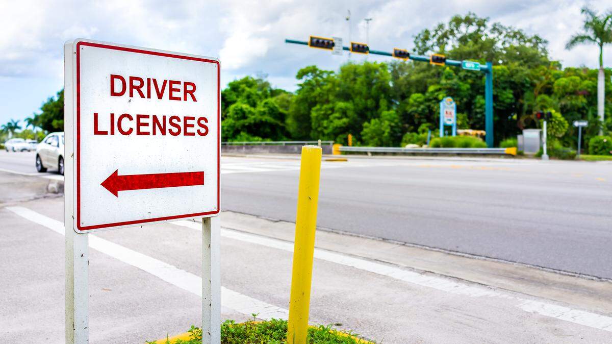 Naples, Florida downtown street empty road with roadside sign signpost for directions to driver license office for renewal or people who relocated