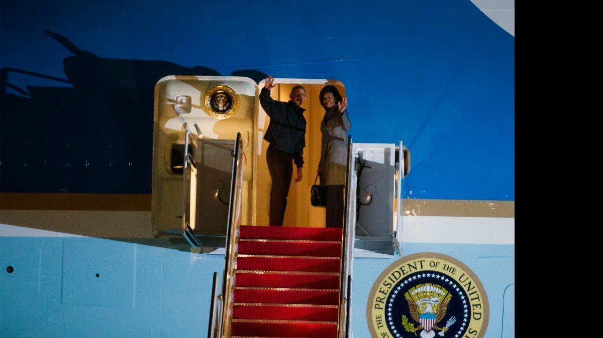 El presidente Barack Obama y la primera dama Michelle Obama saludan desde el Air Force One antes del despegue, en la Base Andrews de la Fuerza Aérea, Md., el sábado, 24 de enero 2015, durante un viaje a Nueva Delhi, India, a través de la base aérea de Ramstein, Alemania.