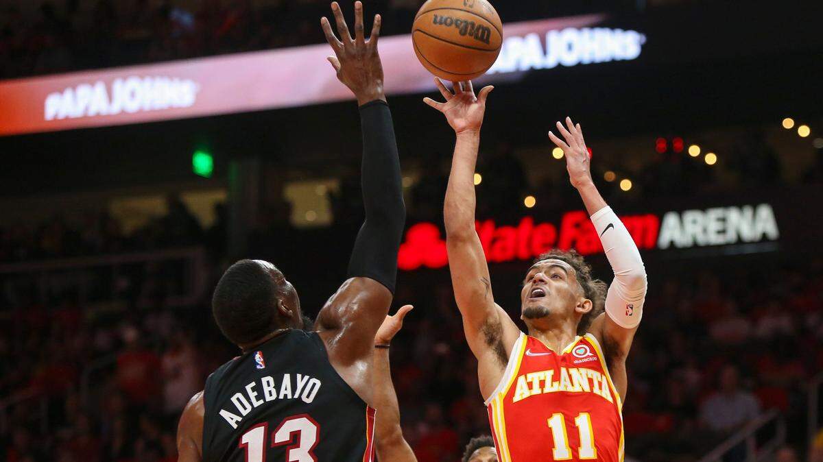 El armador de los Atlanta Hawks, Trae Young (11), dispara entre el centro de Miami Heat, Bam Adebayo (13), y el armador Kyle Lowry durante la primera mitad del Juego 3 de una serie de playoffs de primera ronda de baloncesto de la NBA el viernes 22 de abril de 2022 en Atlanta.