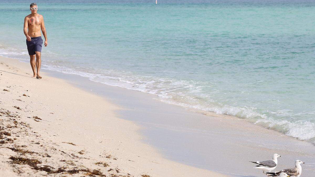 Un hombre camina por la playa en Haulover Beach, donde las autoridades advierten no bañarse después que un desperfecto en una estación de bombeo del noreste del Condado Miami-Dade provocó un derrame masivo de aguas albañales.