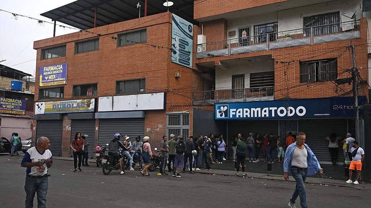 People make a line outside a pharmacy in the Choche neighborhood, in Caracas on January 4, 2026, a day after Venezuela's president Nicolas Maduro was captured in a US strike. A lingering smell of explosives hung over Venezuela's capital Caracas on Saturday as shocked residents took stock after an early-morning US strike that ousted strongman Nicolas Maduro. (Photo by Federico PARRA / AFP via Getty Images)