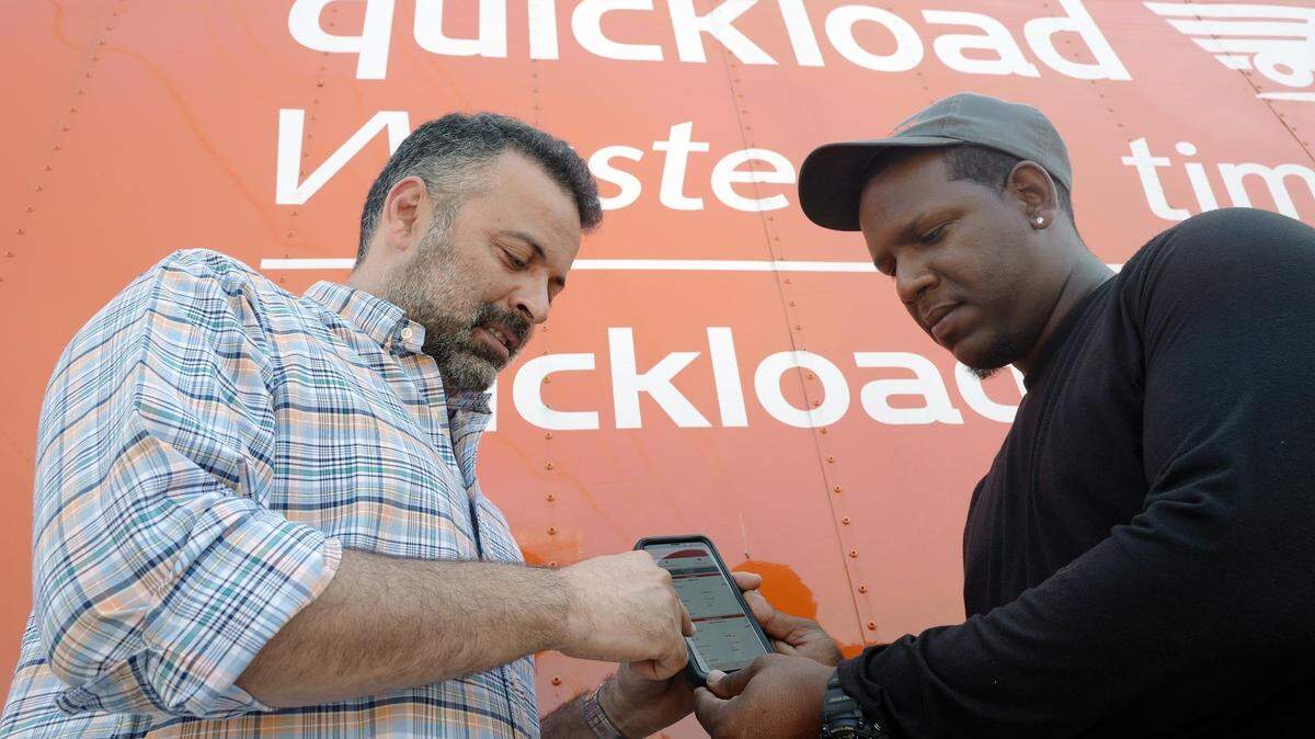 Ozan Baran (izquierda ), fundador de Quickload, con el chofer de camión Nelson Bautista, observan cómo se usa la aplicación Quickload, de la cual se están beneficiando muchos camioneros hispanos.