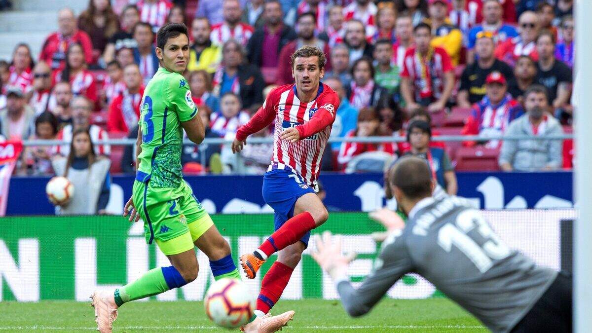 El delantero del Atlético de Madrid Antoine Griezmann (centro) intenta batir al portero del Real Betis Pau López durante el partido de la octava jornada de la liga española, el 7 de octubre de 2018 en Madrid.