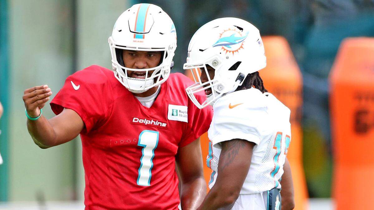 El quarterback de los Dolphins Tua Tagovailoa (izq.) y el wide receiver Jaylen Waddle conversan en un entrenamiento del equipo el 8 de agosto de 2021 en Miami Gardens, Florida.