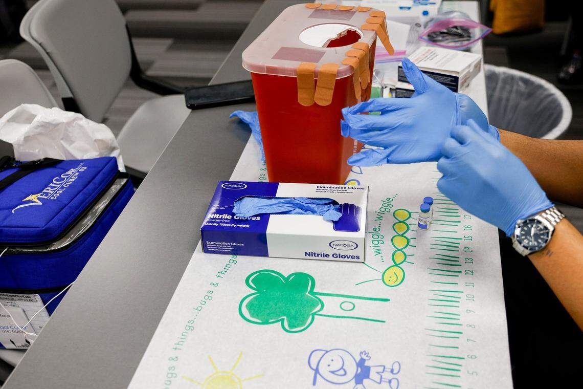 A nurse puts on gloves before preparing MMR vaccines — the single dose targets measles, mumps and rubella. 
