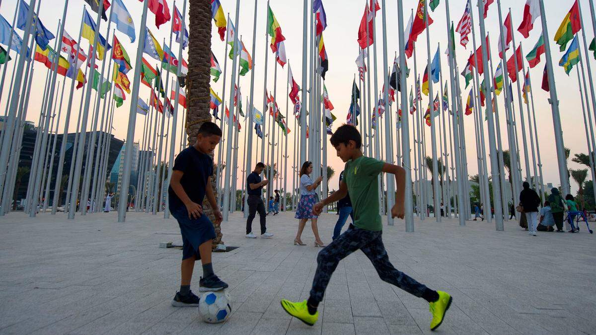 Niños juegan al fútbol en una plaza de Doha, capital de Catar, rodeada de las banderas de las selecciones participantes en el próximo Mundial de fútbol.
