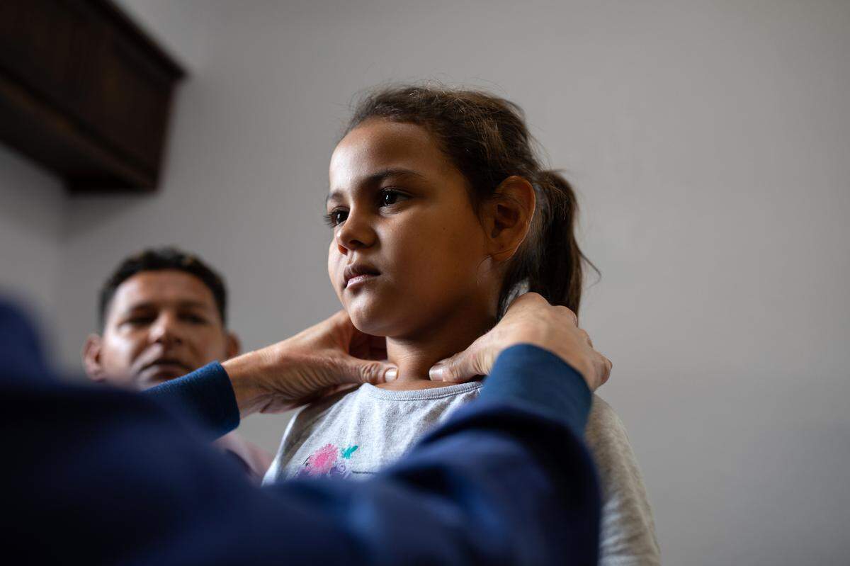 El Dr. Lauren Herbert, pediatra voluntario examina a una niña hondureña en la clínica de salud de la Caridades Católicas en McAllen, Texas.