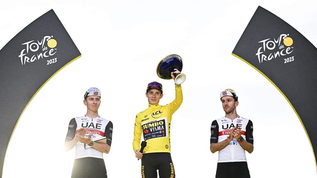 El ciclista danés Jonas Vingegaard (centro) subió a lo más alto del podio en el Tour de Francia, escoltado por el esloveno Tadej Pogacar (izq.) y el británico Adam Yates, el domingo 23 de julio de 2023 en París.