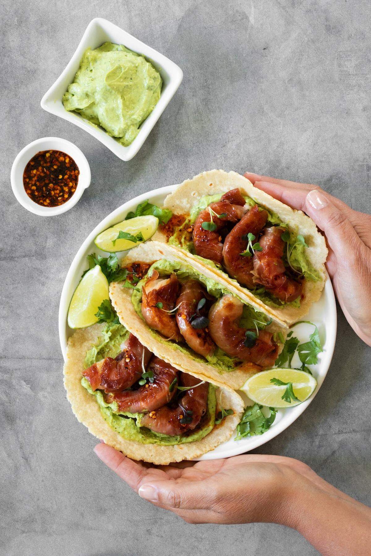 Tacos de camarón envueltos en jamón con salsa de aguacate y miel macha.