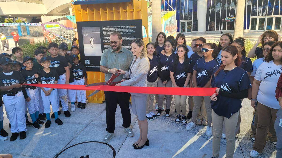 La presidenta de Operaciones Comerciales de los Marlins, Caroline O’Connor, y Dennis Rivera Pichardo, Director de Fotografía de El Nuevo Día, cortan la cinta inaugural de la exposicion “3,000’’ en homenaje a Roberto Clemente.