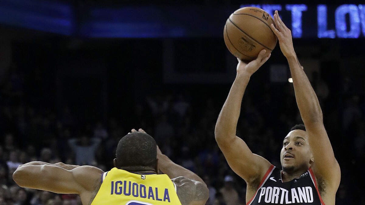 El jugador de Portland CJ McCollum tira al aro ante la marca de Andre Iguodala, de los Warriors, en el partido efectuado el 27 de diciembre de 2018.
