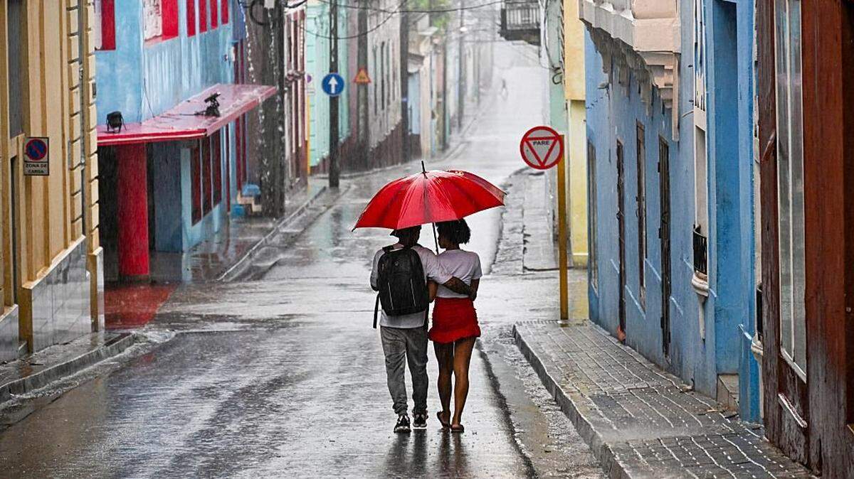 A couple walks in a street before Hurricane Melissa hits the city of Santiago de Cuba, Cuba, on October 28, 2025. (Photo by YAMIL LAGE / AFP) (Photo by YAMIL LAGE/AFP via Getty Images)