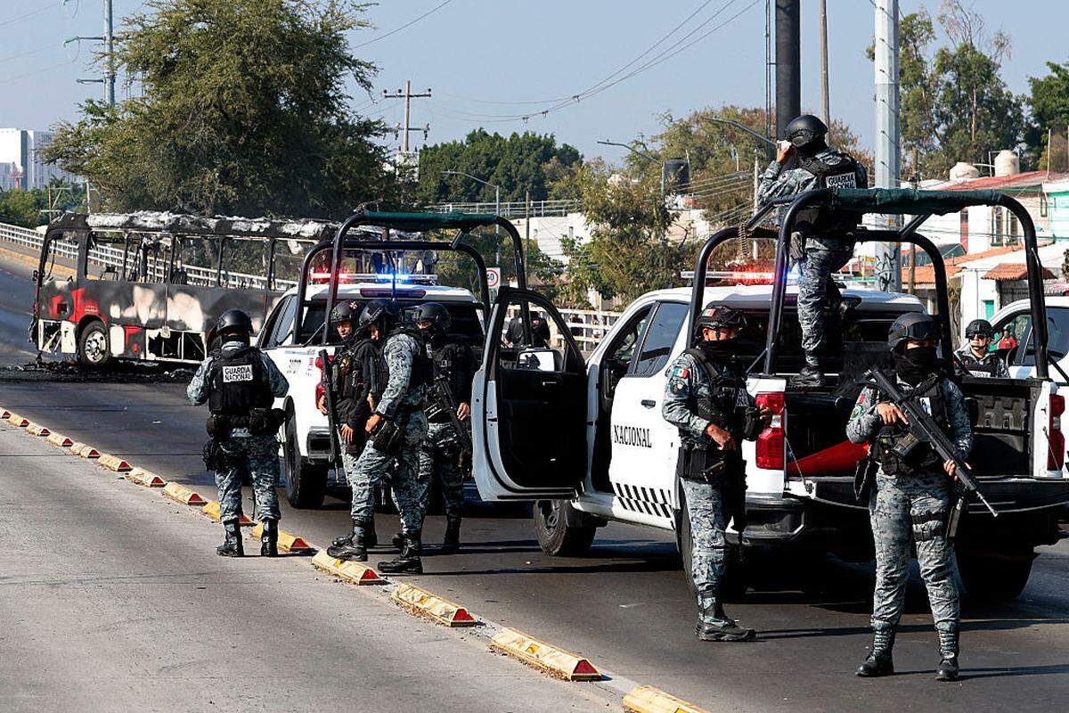 Miembros de la Guardia Nacional se encuentran cerca de un autobús quemado por grupos del crimen organizado en respuesta a una operación en Jalisco para arrestar a un objetivo de seguridad de alta prioridad, en una de las principales avenidas de Zapopan, estado de Jalisco, México, el domingo 22 de febrero de 2026.