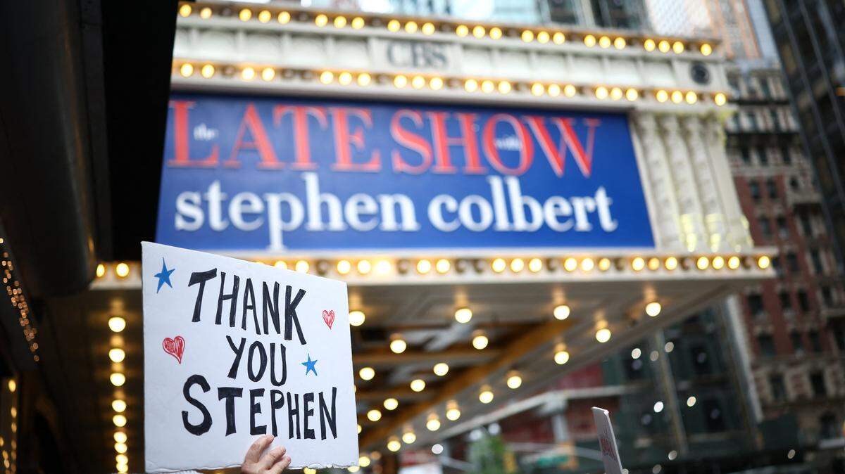 Personas sostienen carteles en apoyo a Stephen Colbert frente al Teatro Ed Sullivan antes de la grabación del episodio final de ‘The Late Show’, tras 32 años en antena, en Nueva York, el 21 de mayo de 2026.