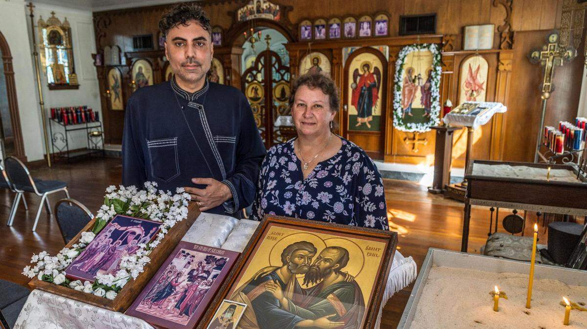 El diácono Georgios Zervos y Susan Homyk, miembro de larga data de la iglesia, posan frente al santuario de la iglesia grecocatólica ortodoxa rusa de los Santos Pedro y Pablo en La Pequeña Habana, una de las parroquias ortodoxas orientales más antiguas de Miami, que también es el hogar restaurado del primer alcalde de Miami.
