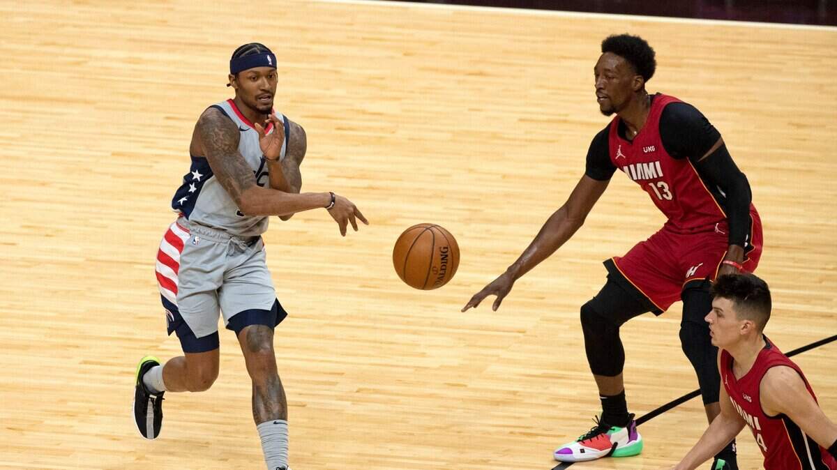 El escolta de los Wizards Bradley Beal (3) pasa el balón ante los jugadores del Heat Bam Adebayo (13) y Tyler Herro (14) el miércoles 3 de febrero de 2021 en el AmericanAirlines Arena .