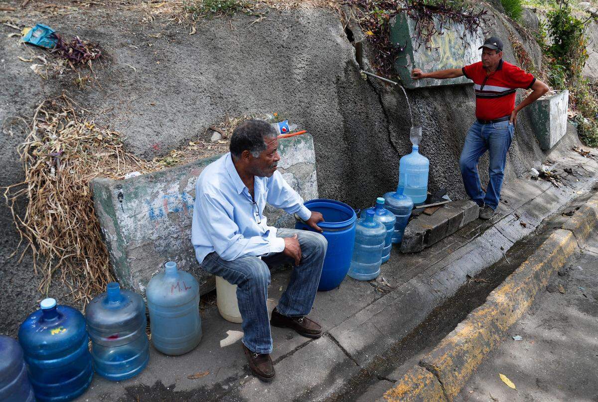 Men fill containers with water at Avila National Park during rolling blackouts which has cut many off from running water in Caracas, Venezuela, Wednesday, March 13, 2019. Blackouts have marked another harsh blow to a country paralyzed by turmoil as the power struggle between Venezuelan President Nicolas Maduro and opposition leader Juan Guaido stretched into its second month. (AP Photo/Eduardo Verdugo)