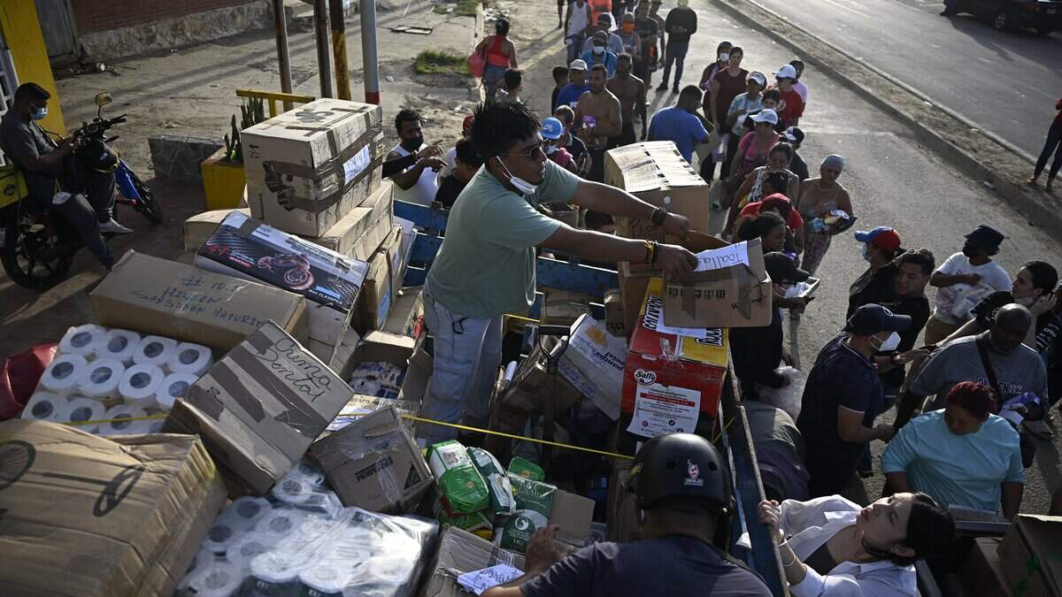 Volunteers distribute medicines and basic supplies to residents affected by twin earthquakes in the Playa Verde sector of Catia La Mar, La Guaira state, Venezuela, on June 29, 2026. Hopes were fading of finding survivors more than four days after powerful twin earthquakes struck Venezuela, as residents grow increasingly frustrated with the government's response to the disaster that has killed -up to now- more than 1,700 people and left tens of thousands unaccounted for. (Photo by Federico PARRA / AFP via Getty Images)