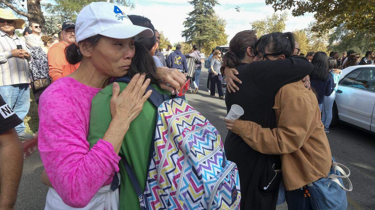 Dos estudiantes se reúnen con sus padres después de un tiroteo en Saugus High School, en donde al menos dos jóvenes murieron, el jueves en Santa Clarita, California.