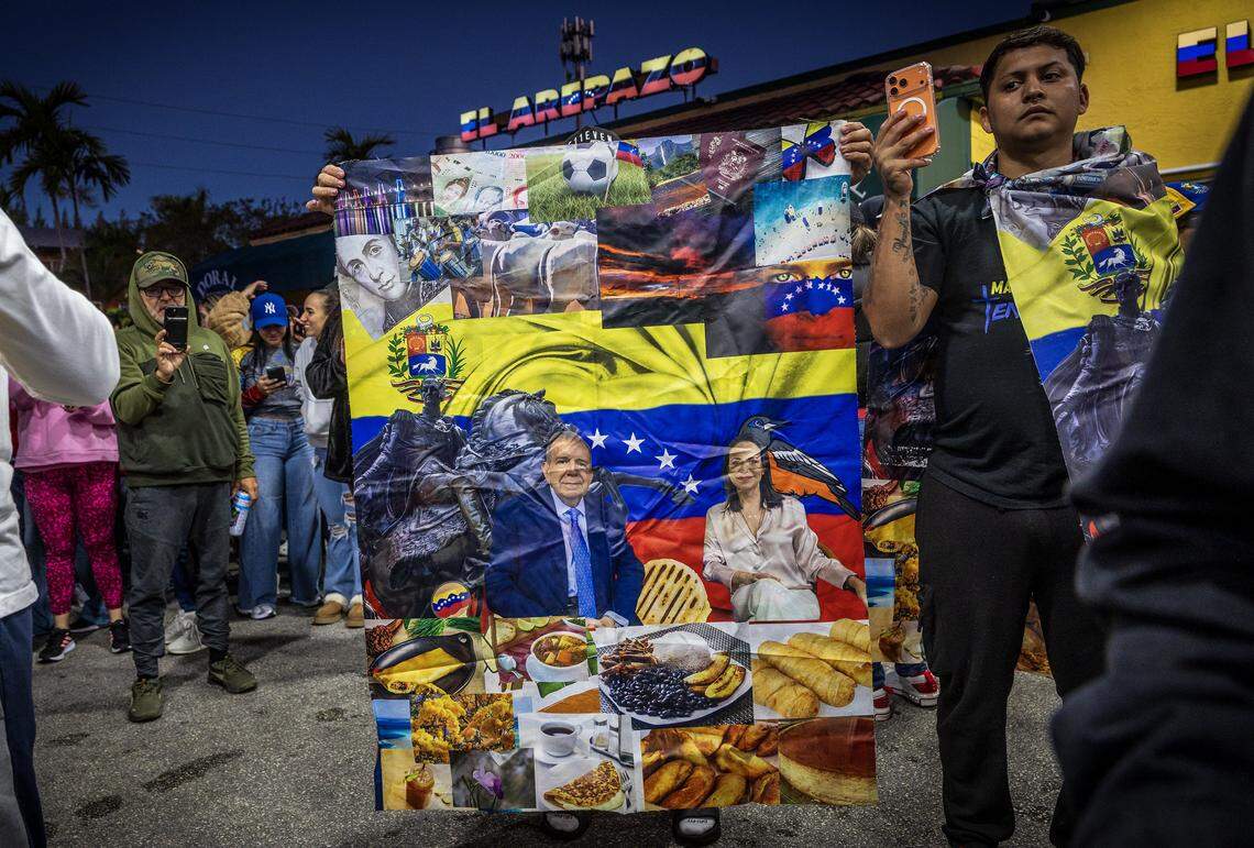 Un hombre muestra una pancarta con una foto de los líderes opositores María Corina Machado y Edmundo González Urrutia, mientras se unía a un grupo de venezolanos exiliados que viven en el sur de Florida celebrando frente a El Arepazo, en Doral, Florida, después de que Estados Unidos capturara Nicolás Maduro, el 3 de enero de 2026.