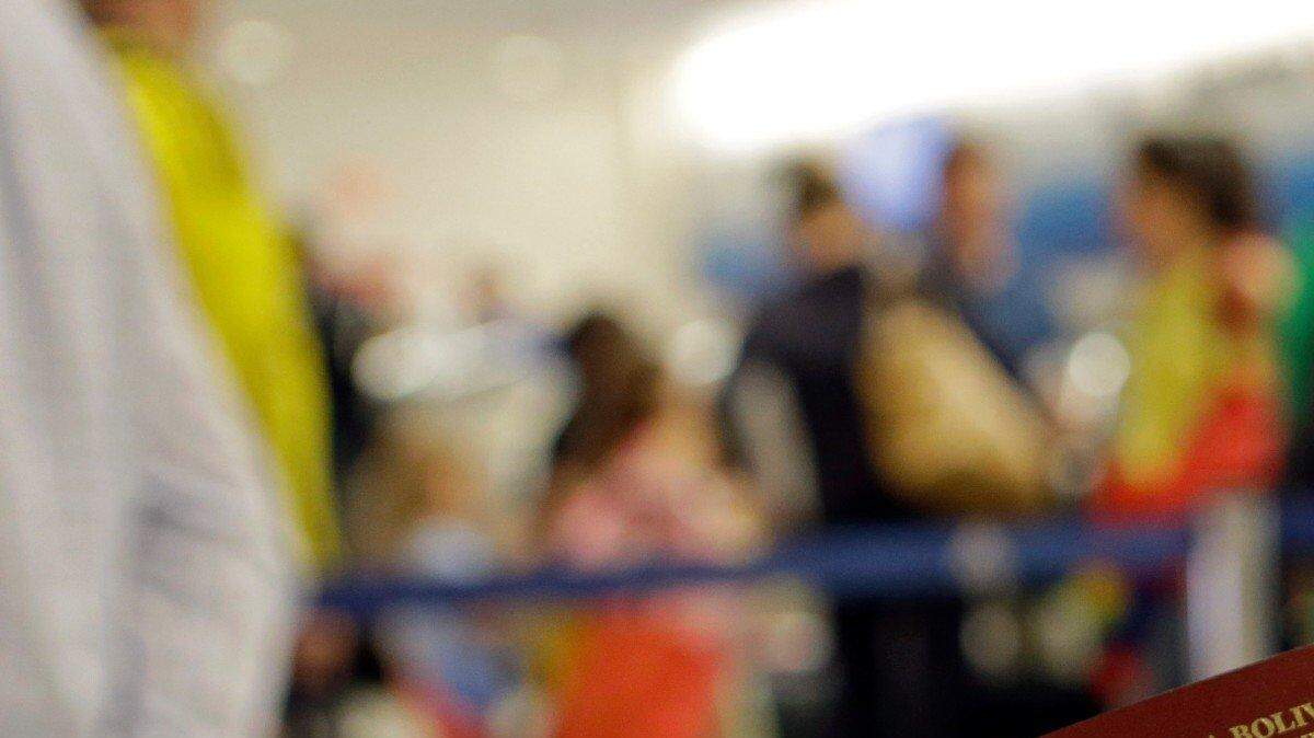 Un pasajero tiene su pasaporte venezolano mientras se prepara para viajar a Venezuela desde el Aeropuerto Internacional de Miami. Foto de archivo.