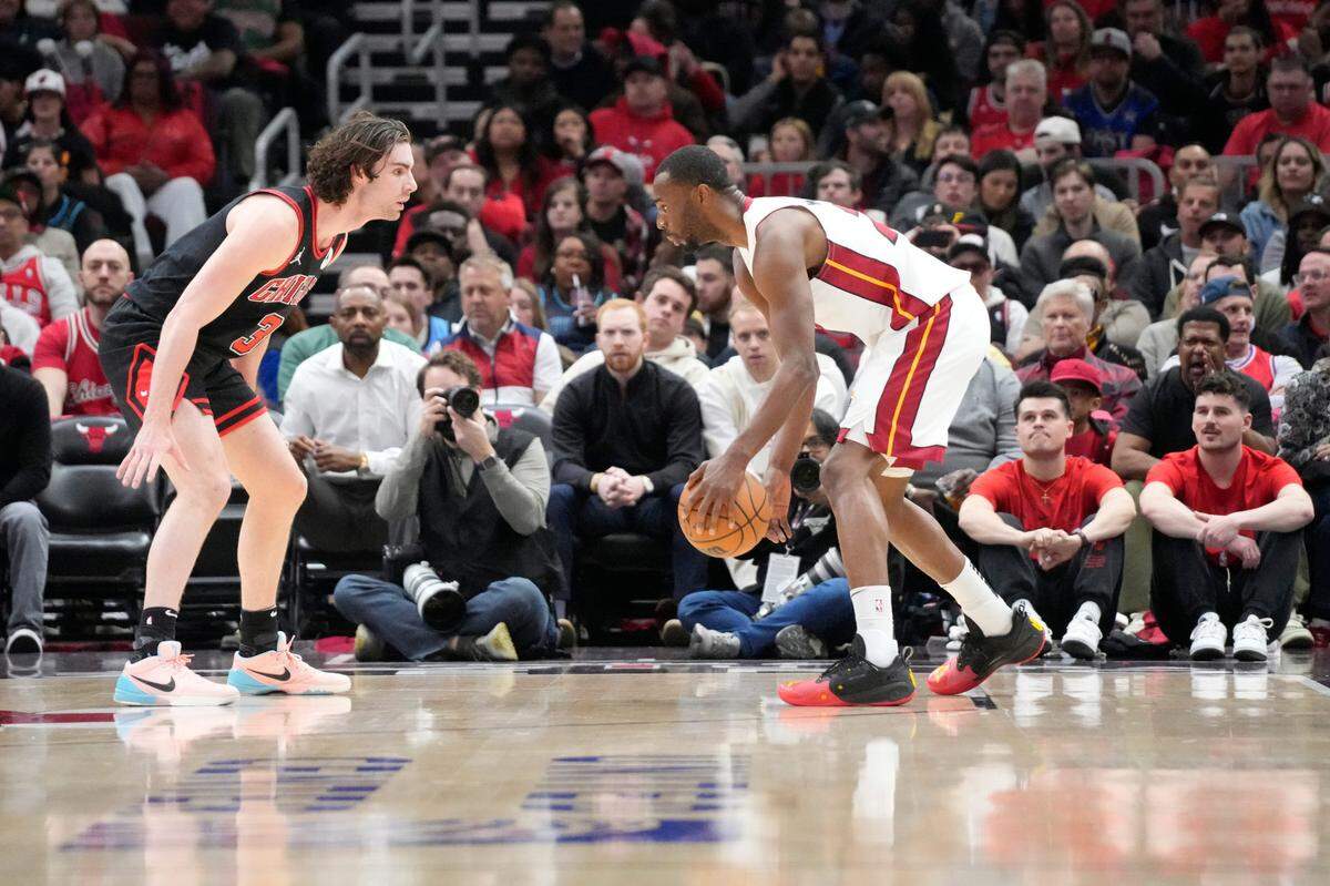 El jugador del Heat de Miami Andre Wiggins (der.) trata de pasar la marca de Josh Giddey, de los Bulls, en el partido del play-in celebrado el 16 de abril de 2025 en Chicago.