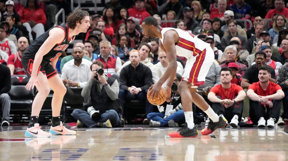 El jugador del Heat de Miami Andrew Wiggins (der.) trata de pasar la marca de Josh Giddey, de los Bulls, en el partido del play-in celebrado el 16 de abril de 2025 en Chicago.