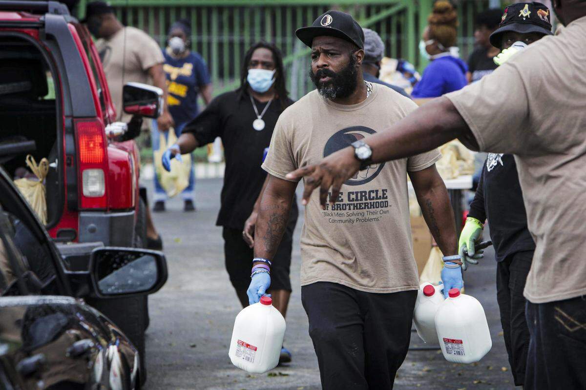 Los voluntarios se apresuran a llenar los baúles de los que vinieron a la donación de alimentos a 6100 NW Second Ave. en Miami, Florida, el 1 de abril de 2020. La organización sin fines de lucro Ark of the City de Elliott se asoció con el rescate de alimentos Farm Share para obtener alimentos donados a las personas necesitadas durante la pandemia de coronavirus a través de los traslados en coche.