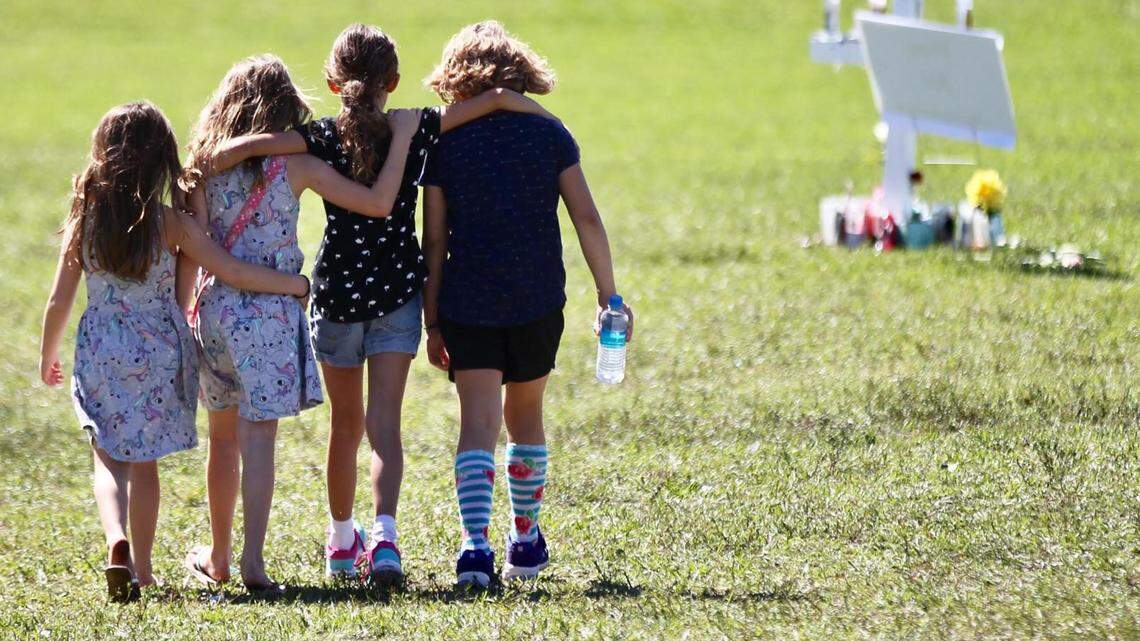 Four children with hands around each other approach a vigil post at Park Trails Park in Parkland honoring the 17 students that were shot at the high school.