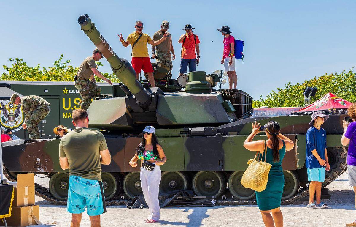 Gente posa sobre un tanque Abrams en exhibición en la villa del Ejército en South Beach mientras el Hyundai Air & Sea Show que regresa para su octavo saludo anual nacional a los Héroes de América en Miami Beach, el sábado 25 de mayo de 2024.