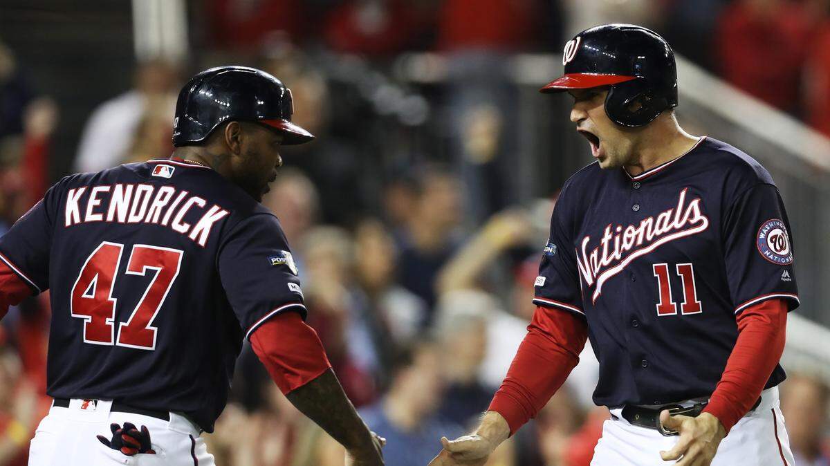 Ryan Zimmerman (der.) celebra con Howie Kendrick después de anotar una carrera para los Nacionales en el primer inning del partido ante los Cardenales, el 15 de octubre de 2019 en Washington.
