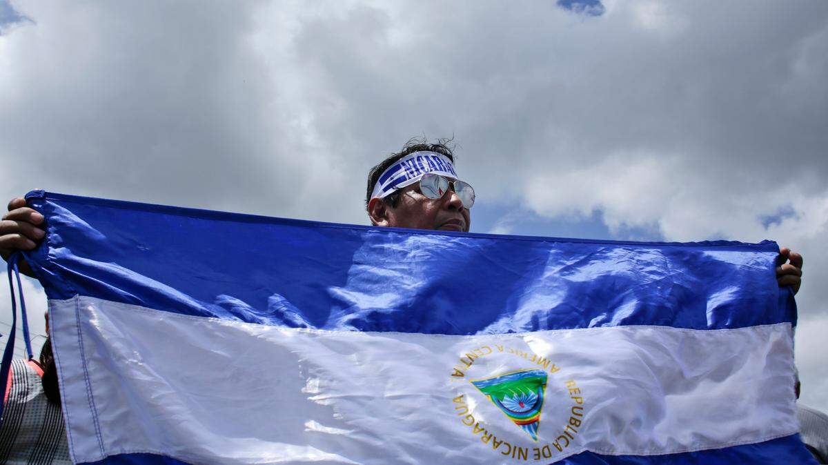 Un manifestante sostiene una bandera de Nicaragua durante una protesta en apoyo a periodistas que fueron atacados cuando cubrían las manifestaciones en contra del gobierno de Daniel Ortega, el 30 de julio de 2018 en Managua.