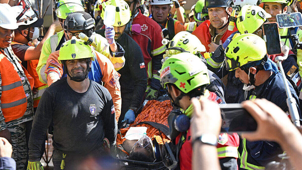Un equipo de rescatistas internacionales transportan a Hernán Gil, un hombre rescatado de los escombros de un edificio, el jueves 2 de julio de 2026, en Catia La Mar, estado La Guaira, Venezuela.