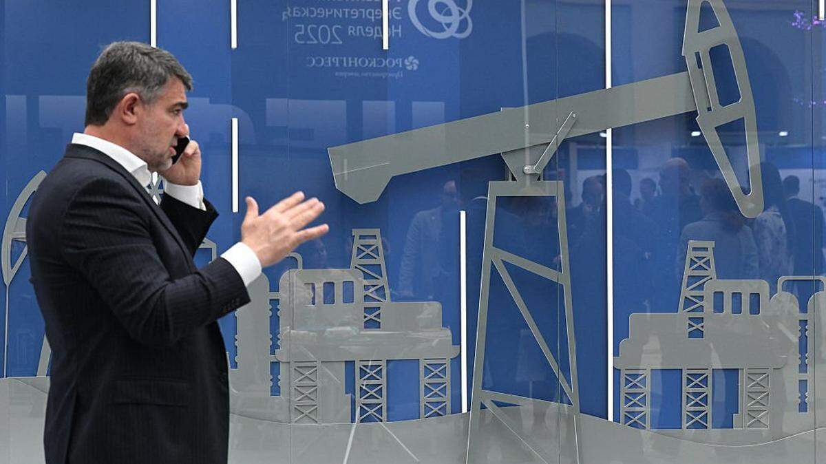 A man speaks on a smartphone in front of an installation featuring an oil pump at an exhibition on the sidelines of the Russian Energy Week forum in Moscow on October 15, 2025. (Photo by Olesya KURPYAYEVA / AFP) (Photo by OLESYA KURPYAYEVA/AFP via Getty Images)