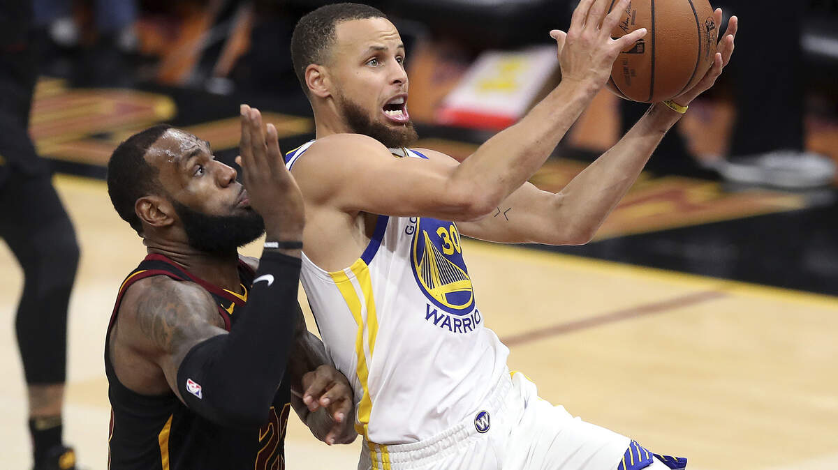 El armador de los Warriors Stephen Curry entra al aro ante la marca de LeBron James, de los Cavaliers, en el tercer partido de la final de la NBA, celebrado el 6 de junio de 2018, en Cleveland.