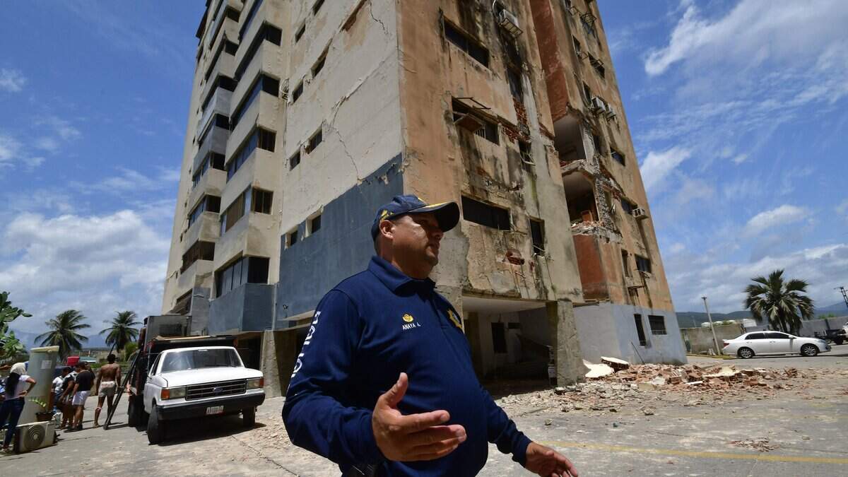 A police officer stands next to damaged building in Moron, state of Carabobo, Venezuela, on June 26, 2026, following deadly earthquakes. Using heavy equipment or their bare hands, rescuers and volunteers searched for survivors of the twin earthquake in Venezuela, which has officially left 589 dead and, according to estimates, thousands missing. (Photo by Orlando Obispo / AFP via Getty Images)