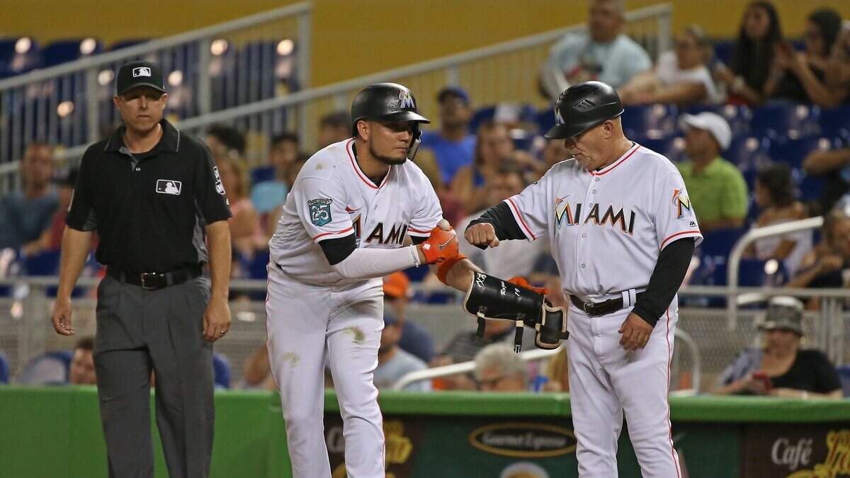 El torpedero de los Marlins Miguel Rojas es felicitado por el coach de primera base Perry Hill tras batear un hit en un partido contra los Cerveceros, el 11 de julio de 2018.