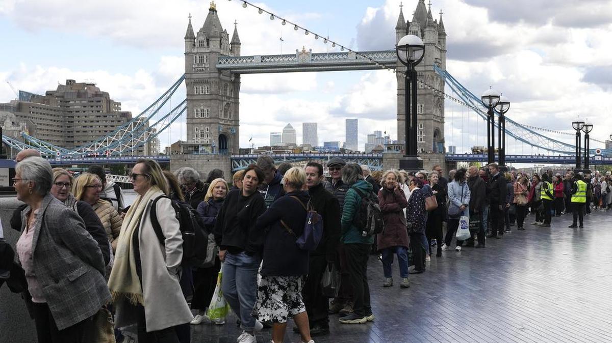 La gente espera en una fila frente al Puente de la Torre para presentar sus respetos a la difunta Reina Isabel II durante el Estado Acostado, en Westminster Hall, Londres, el viernes 16 de septiembre de 2022. (AP foto/Markus Schreiber)