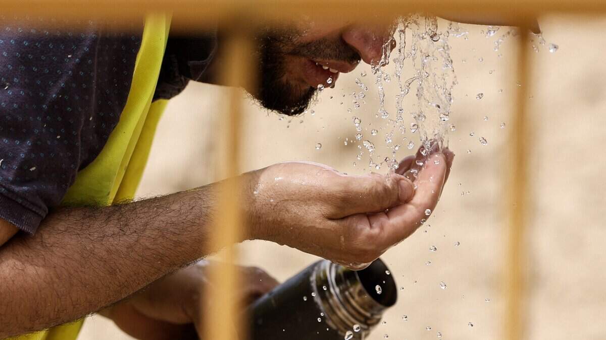 A worker cools off with water at a road construction site in Madrid on June 22, 2026, during the heat wave affecting the Iberian Peninsula. National weather agency AEMET issued an orange heat warning  the second-highest level - for the Madrid region, with temperatures forecast to reach 40C. Large parts of Spain experience unusually high temperatures for June as a mass of hot air from North Africa moves across the Iberian Peninsula. (Photo by OSCAR DEL POZO / AFP via Getty Images)
