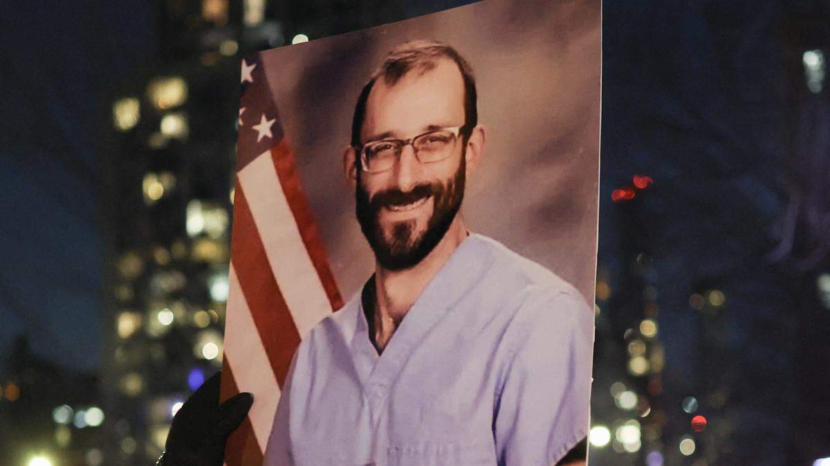 A man holds a portrait of Alex Pretti, a 37-year-old nurse who was fatally shot by immigration agents in Minneapolis, during a vigil for him at the Veterans Affairs NY Harbor Healthcare System Manhattan Campus in New York, on January 29, 2026. US President Donald Trump said on January 27 that he would "de-escalate a little bit" in Minneapolis after the fatal shootings of two civilians fueled a storm of criticism over his signature immigration crackdown. (Photo by ANGELA WEISS / AFP via Getty Images)