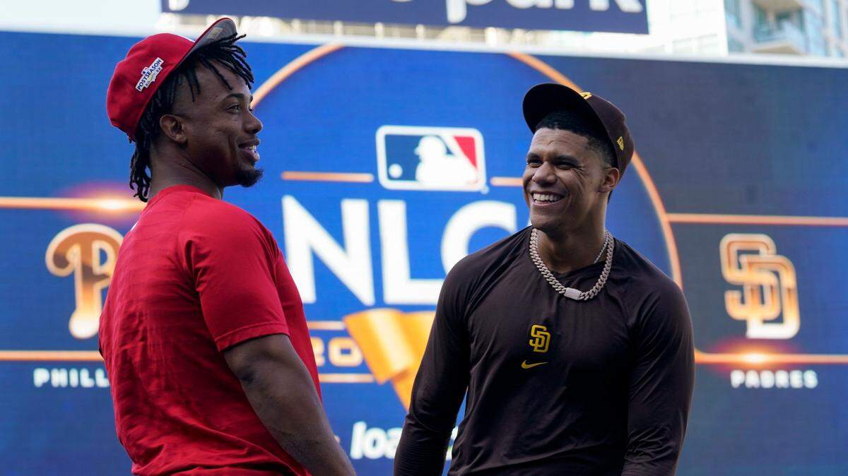 El jardinero de los Padres Juan Soto (der.) bromea con el segunda base de los Filis de Filadelfia Jean Segura durante una práctica celebrada el 17 de octubre de 2022 en San Diego.
