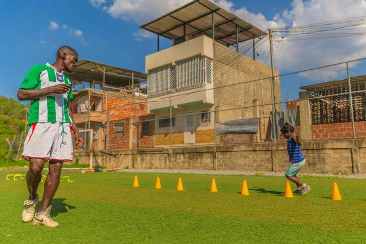 Estelita Gómez, de 7 años, entrena en el calor de la tarde en Petare, Venezuela. El entrenador Iván Torres le enseña a saltar obstáculos rápidamente.