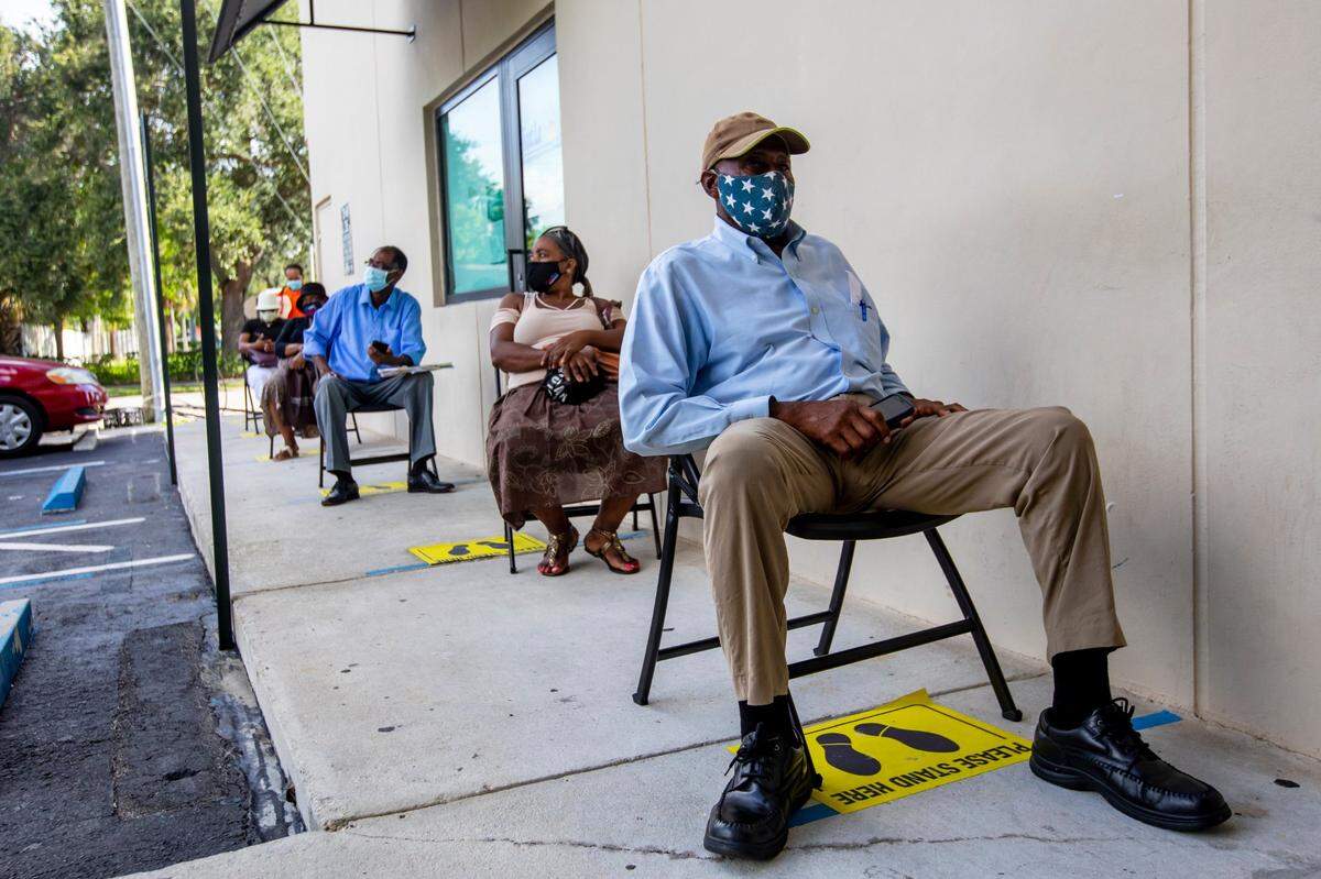 Perejona Lavenal is socially distanced while seated outside as he awaits his turn for assistance with unemployment at Sant La Haitian Neighborhood Center in North Miami, Florida on Aug. 11, 2020.
