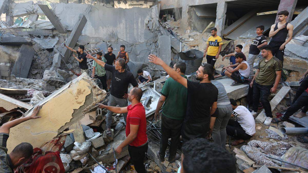 Decenas de personas buscan sobrevivientes entre los escombros de edificios destruidos por los bombardeos israelíes, en la ciudad de Rafah, sur de Gaza, el martes 31 de octubre de 2023.
