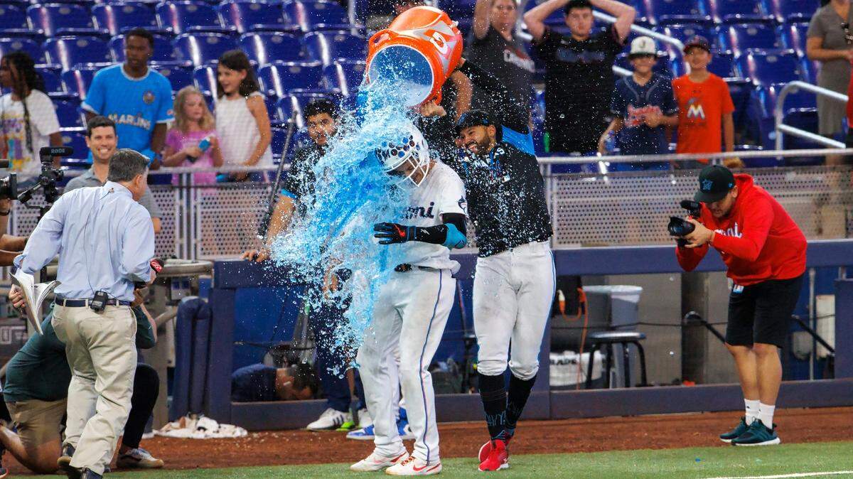 El lanzador Pablo López (der.) baña con la hielera de Gatorade al tercera base de los Marlins Brian Anderson quien conectó el triple que decidió el triunfo ante los Piratas de Pittsburgh, el 14 de julio de 2022 en Miami.